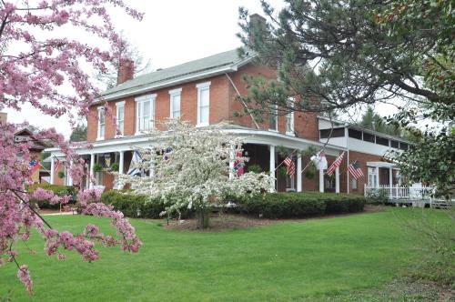 A charming brick house surrounded by blooming trees and flags, set in a lush green yard.