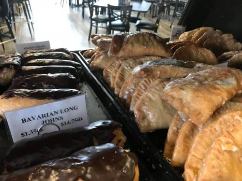 A display of assorted pastries, including Bavarian long johns and flaky pastries, in a bakery setting.