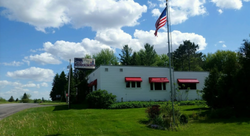 A white building with red awnings, an American flag, and a sign reading "Stanton's" against a blue sky with clouds.