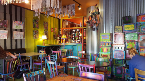 Colorful café interior with eclectic furniture, vibrant wall art, and a cozy atmosphere.