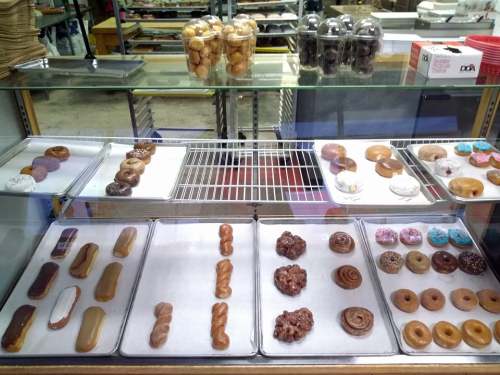 A display case filled with various donuts, including glazed, chocolate, and sprinkled varieties.