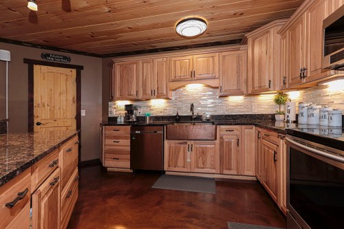 A modern kitchen with wooden cabinets, granite countertops, and stainless steel appliances, featuring a cozy, rustic design.