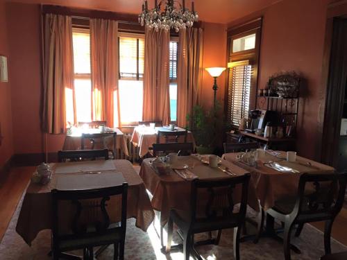 Cozy dining room with tables set for breakfast, warm lighting, and large windows draped with curtains.
