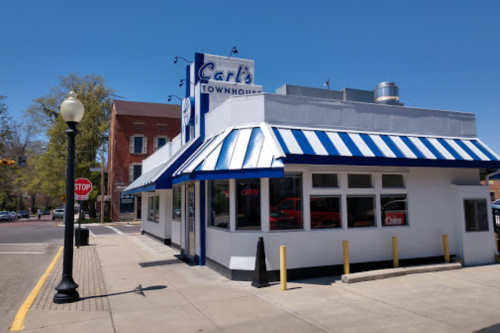 A corner restaurant with a blue and white striped awning, sign reading "Carl's Townhouse," and an open sign in the window.