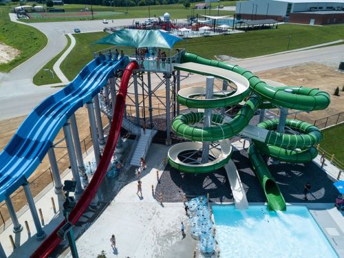 Aerial view of a water park featuring colorful slides, a pool, and people enjoying the attractions.