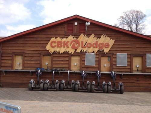 Exterior of CBK Lodge with a wooden facade and several scooters lined up in front.