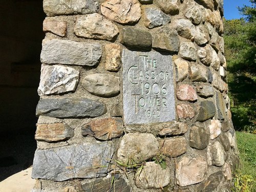 Stone tower with a plaque reading "The Class of 1906 Tower 1944" set in a natural landscape.