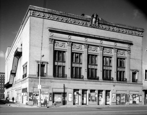 Historic building with ornate architectural details, featuring large windows and decorative friezes, in black and white.