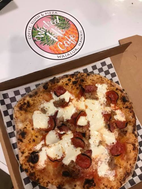 A delicious pizza topped with pepperoni, sausage, and mozzarella, next to a logo for Wicked Cafe in Waialua, Hawaii.