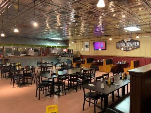 Interior of a casual cafe with tables, chairs, and a counter, featuring a sign that reads "The Downtowner Casual Cafe."