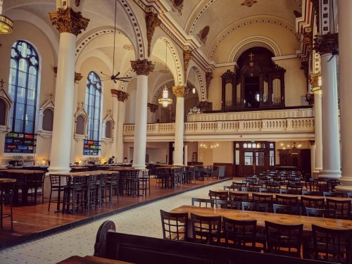 A spacious, elegant interior of a restaurant with high ceilings, arches, and wooden tables arranged for dining.