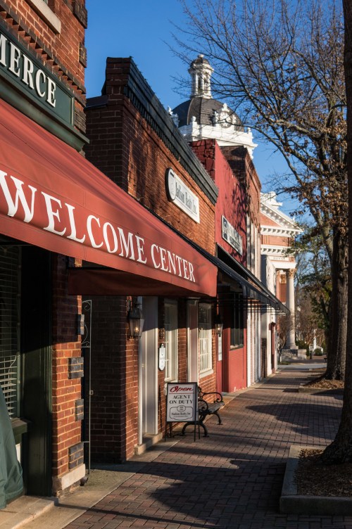 A street view featuring a Welcome Center with brick buildings and a clear blue sky.