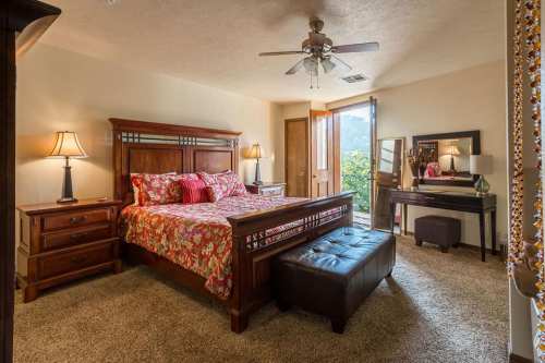Cozy bedroom with a floral bedspread, wooden furniture, and an open door leading to a scenic view outside.