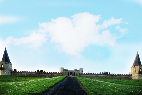 A grand castle with two tall towers, set against a blue sky and green grass, leading up a winding path.