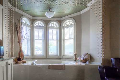 A luxurious bathroom featuring a large tub, decorative windows, and elegant decor with soft lighting.