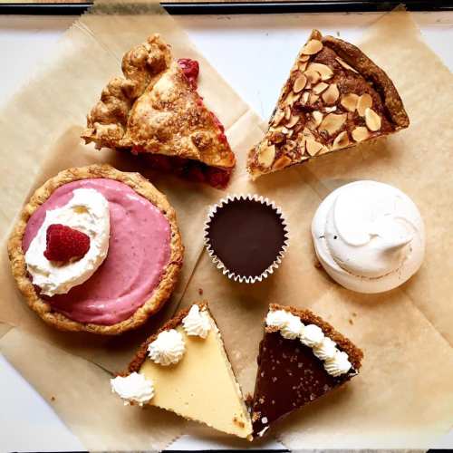 A variety of desserts including pies, a chocolate cup, and meringue arranged on parchment paper.