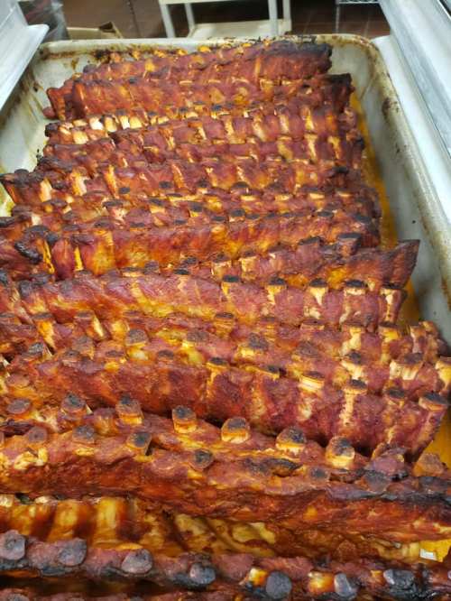 A tray of perfectly cooked, smoky barbecue ribs with a rich, caramelized glaze.