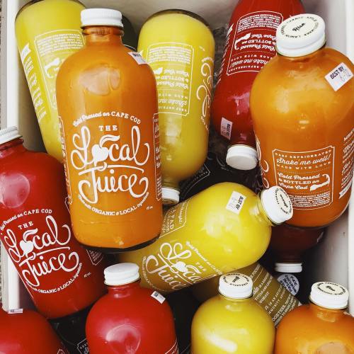 A variety of colorful juice bottles with playful labels, stacked together in a crate.