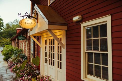 Exterior of Millwright's Restaurant, featuring a red wooden facade, white trim, and colorful flowers at the entrance.