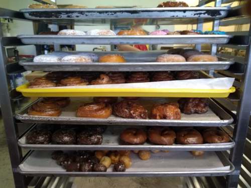 A metal rack filled with various types of donuts, including glazed, powdered, and chocolate varieties.