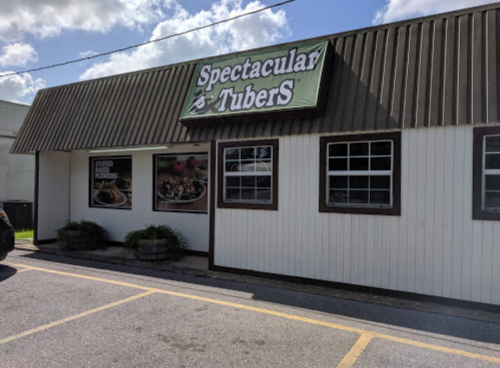 Exterior of a restaurant named "Spectacular Tubers," featuring a green sign and large windows.