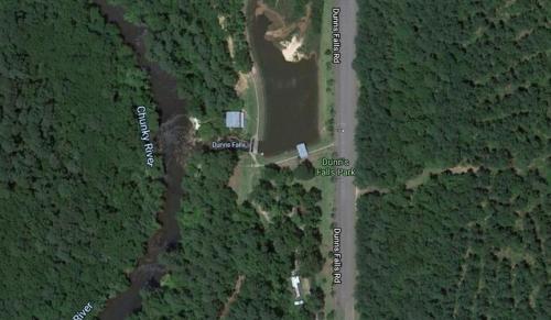 Aerial view of Dunis Falls Park, featuring a pond, surrounding trees, and nearby roads along the Chunky River.