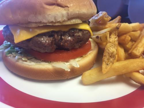 A cheeseburger with lettuce, tomato, and fries on a plate.