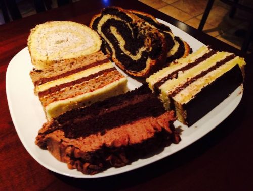A platter of assorted cakes, including chocolate, yellow, and marble varieties, beautifully arranged on a white plate.