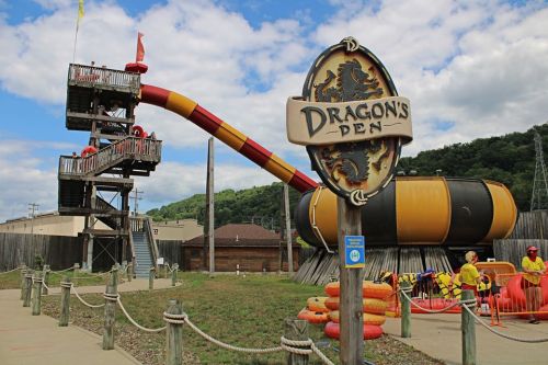 A water slide attraction named "Dragon's Den" with a tower and colorful slide, surrounded by safety equipment and staff.