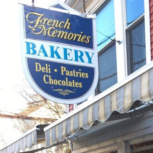 Sign for "French Memories Bakery" featuring deli, pastries, and chocolates, hanging above a storefront.