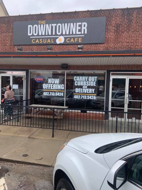 Exterior of the Downtowner Casual Cafe with signs for carryout and delivery services. A car is parked nearby.
