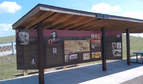 Information display about the birthplace of a legend, featuring historical images and text under a wooden shelter.