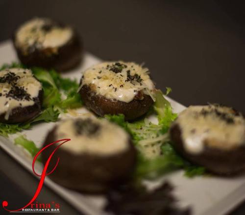 Stuffed mushrooms topped with cheese and herbs, served on a bed of fresh greens.