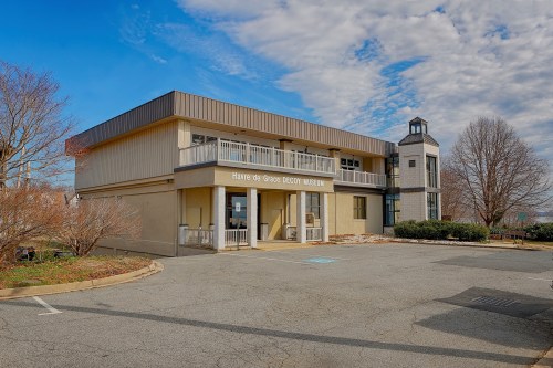 Exterior view of the Héritage de Grace Decoy Museum, featuring a modern building and a small tower, under a cloudy sky.