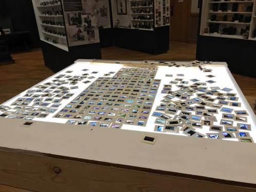 A table illuminated from below, displaying numerous slides arranged in a grid and scattered around the edges.