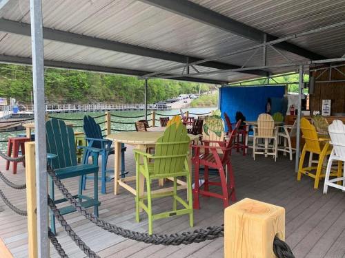 Colorful outdoor seating area with wooden chairs and tables under a covered pavilion by a lake.