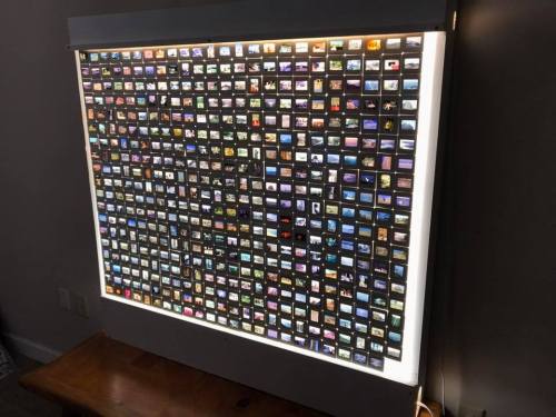A backlit display board filled with numerous small, colorful photo slides arranged in a grid pattern.