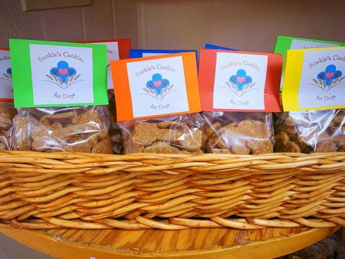 A basket filled with colorful bags of dog cookies, each labeled "Scottie's Cookies for Dogs."