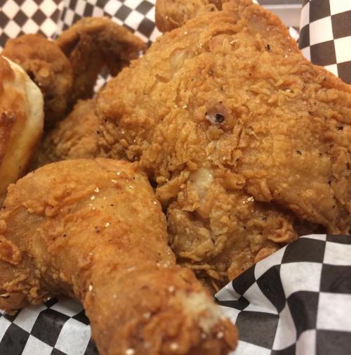 Close-up of crispy fried chicken pieces served in a checkered paper basket.