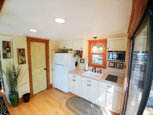Bright kitchen with white cabinets, a sink, refrigerator, and wooden accents, featuring a cozy, inviting atmosphere.