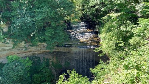 A serene waterfall cascading over rocky cliffs, surrounded by lush green trees and foliage.