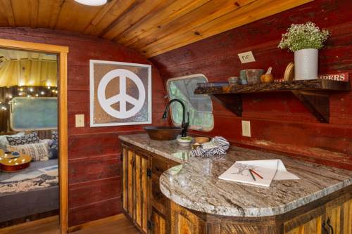 Cozy interior of a vintage trailer with wooden walls, a peace sign art piece, and a rustic countertop.