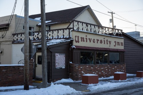 Exterior of University Inn, a two-story building with a sign, surrounded by snow and utility poles.