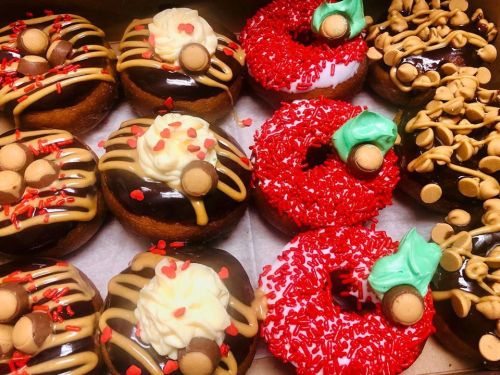 A variety of festive donuts with chocolate glaze, sprinkles, and holiday-themed decorations.