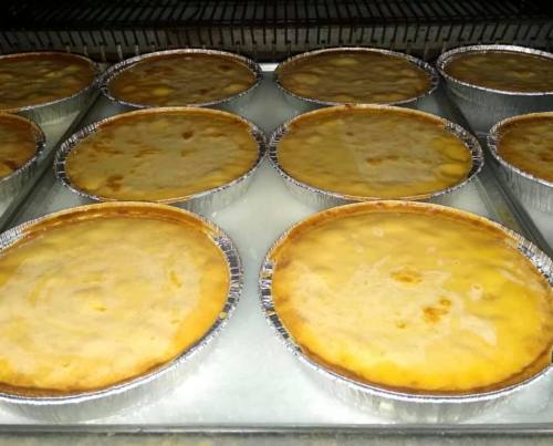 Baking trays filled with golden-brown pies cooling in a refrigerator.
