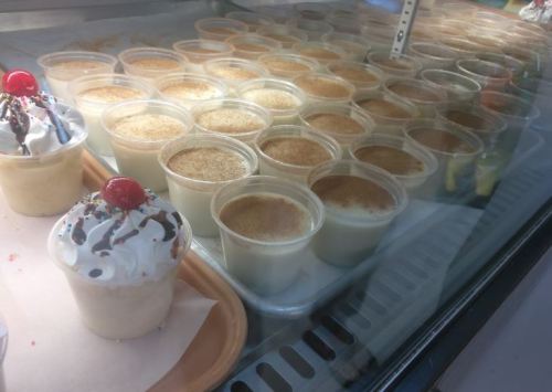 A display of dessert cups, including creamy treats topped with whipped cream, cherries, and sprinkles.