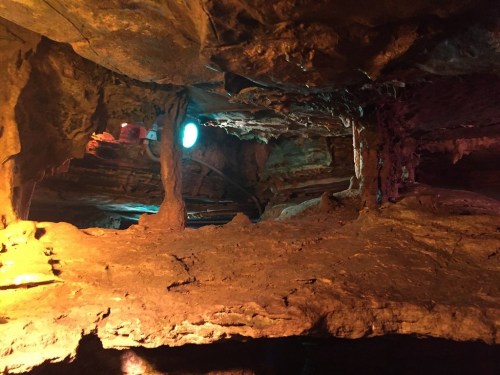 A dimly lit cave interior with rocky formations and a blue light illuminating the space.