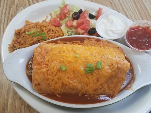 A plate featuring a cheese-covered burrito, rice, salad with tomatoes and olives, sour cream, and salsa.