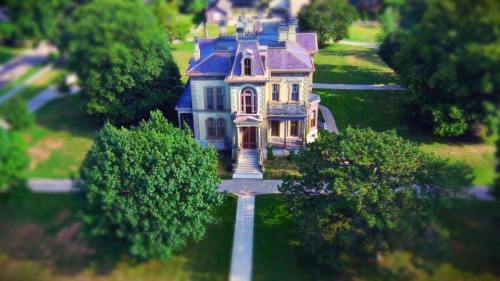 Aerial view of a large, historic mansion surrounded by lush greenery and pathways.
