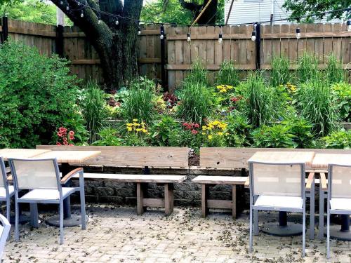 Outdoor seating area with wooden benches and tables, surrounded by vibrant flower beds and greenery.